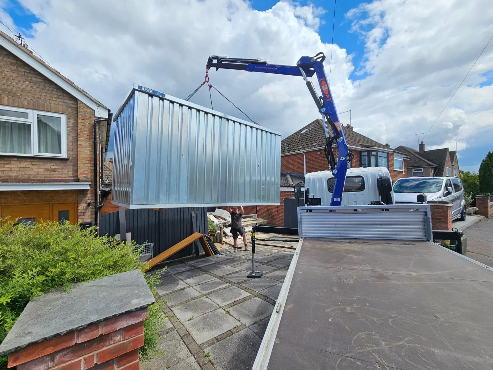 IP&G crane lorry lifting a container into a rear garden