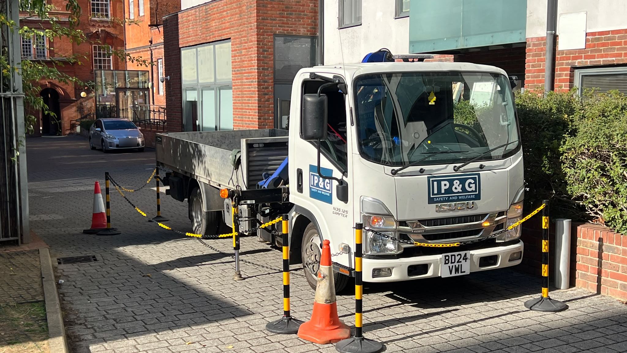 IP&G crane lorry set up behind pedestrian barriers outside a block of flats